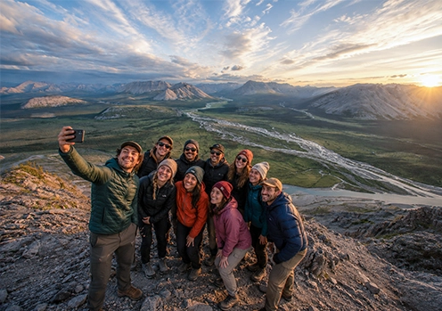 group taking selfie at tombstone during sunrise