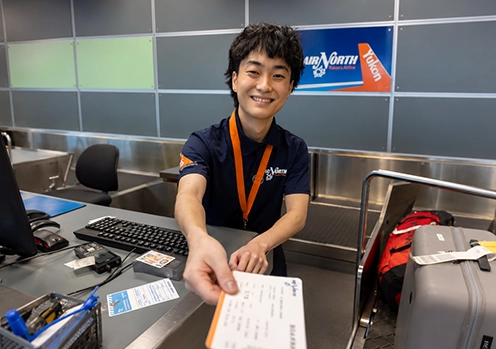 PSA at YVR counter handing a traveller his ticket