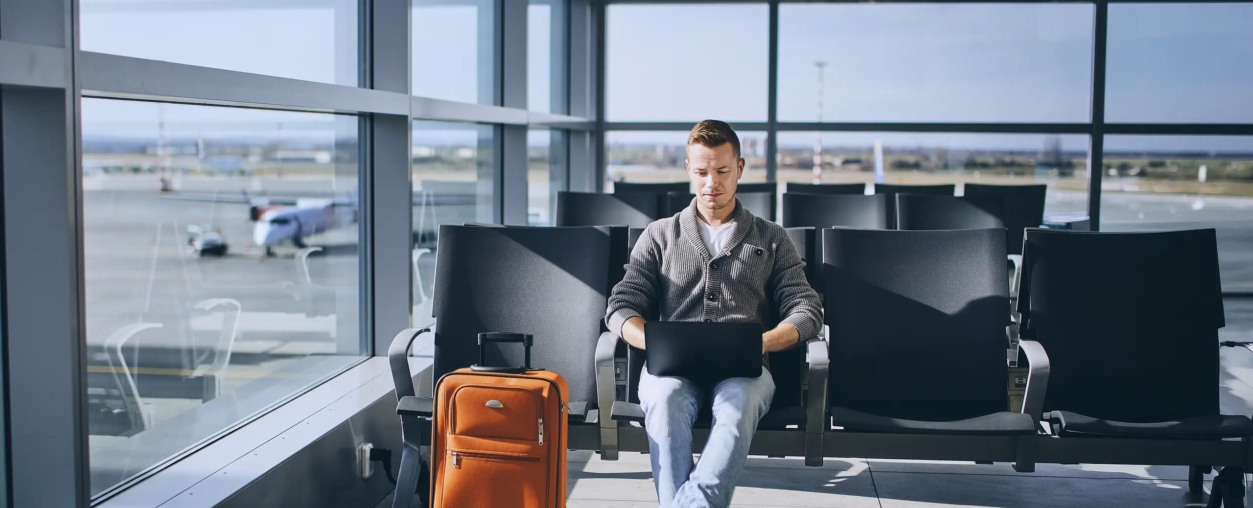 business traveller at airport working on computer waiting for flight